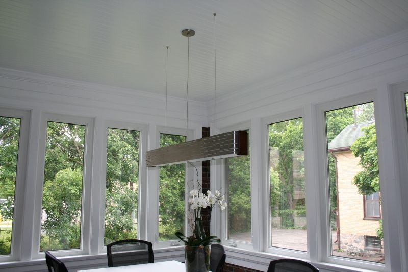 Bright sunroom with windows and a hanging rectangular light fixture.