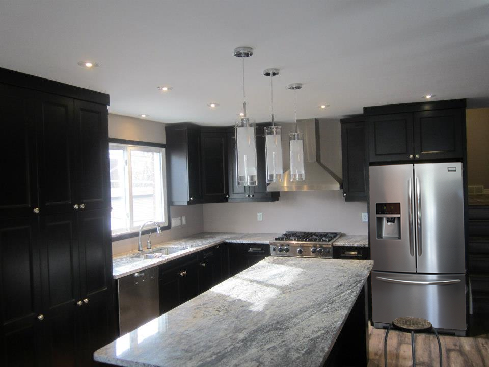 Modern kitchen with black cabinets, stainless steel appliances, and granite countertops.