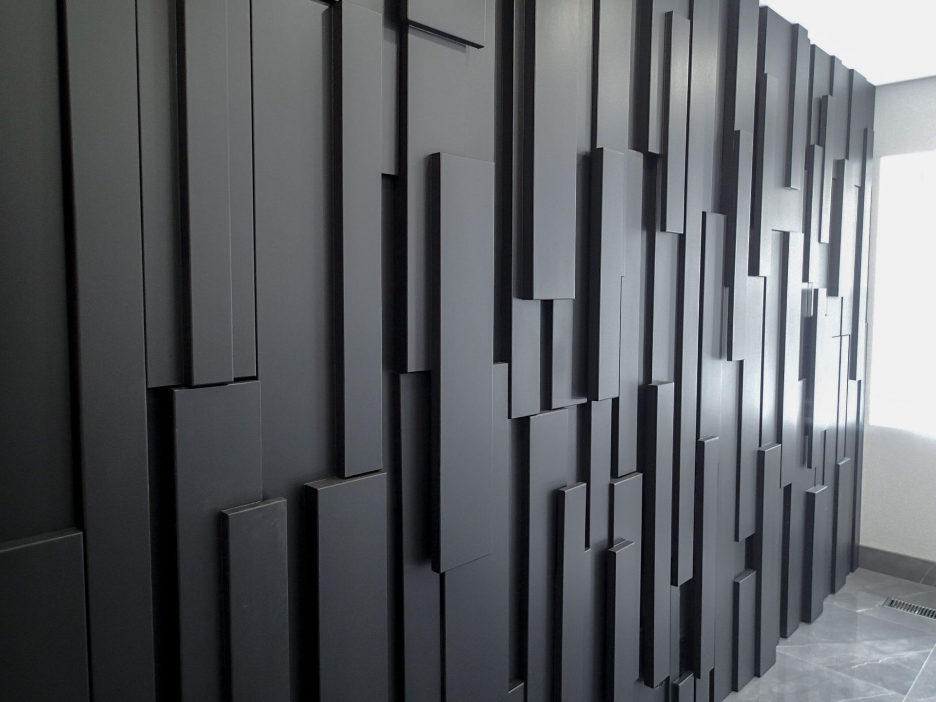 Black textured accent wall with varying vertical rectangular shapes.