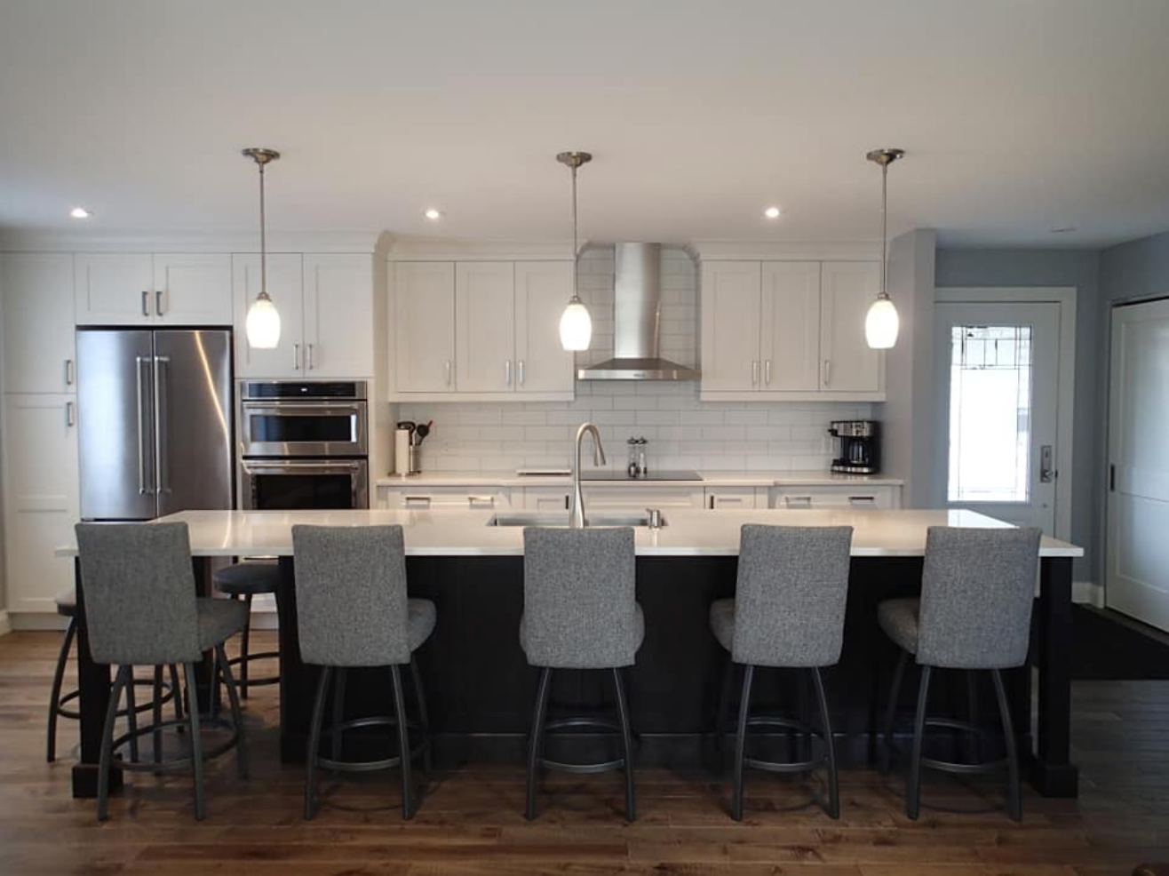Modern kitchen with island, white cabinets, stainless steel appliances, and bar stools.