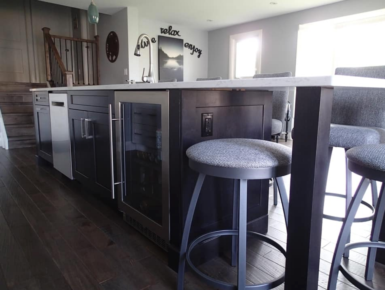 Kitchen island with dark cabinets, stainless steel appliances, stools, and a countertop.
