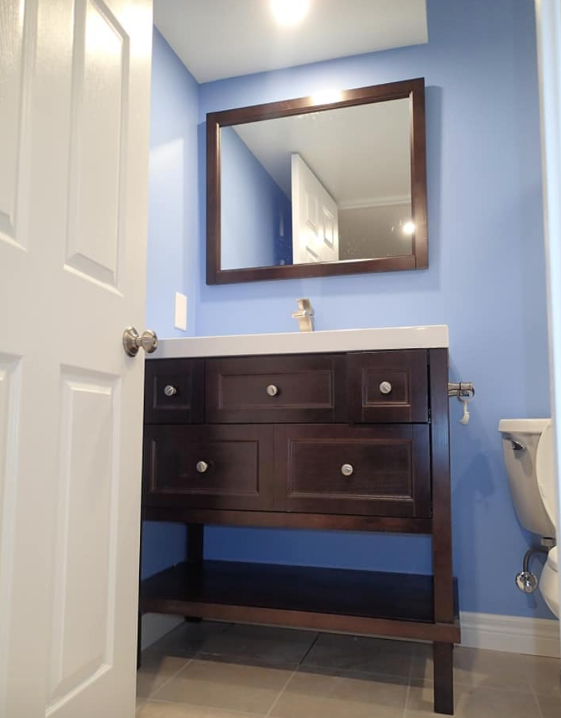Bathroom with dark wood vanity, blue walls, large mirror, and toilet.