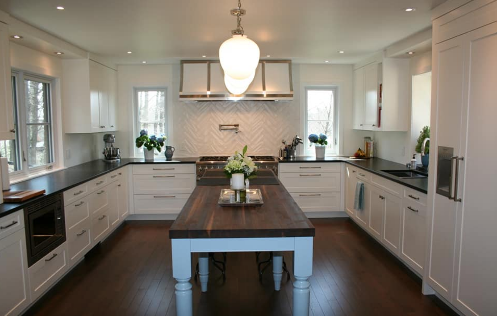 U-shaped white kitchen with dark counters and a dark wood island.