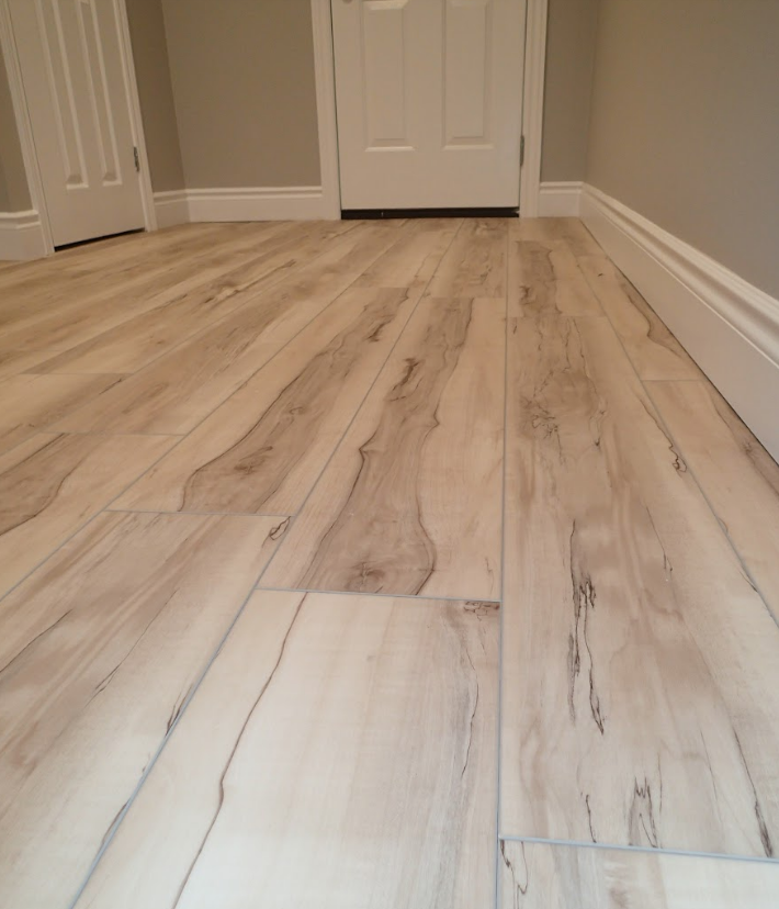 Light wood-look flooring in a room with a door and white trim.