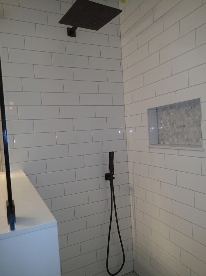 Modern shower with white subway tile, black fixtures, and a recessed shelf.