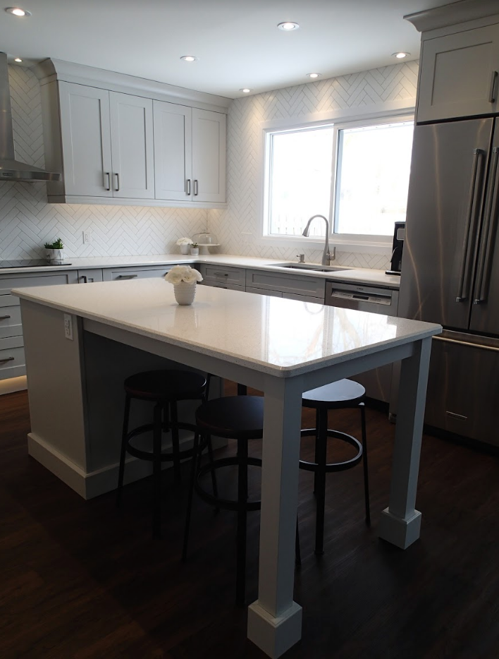 Modern kitchen with a white countertop island, gray cabinets, and stainless steel appliances.