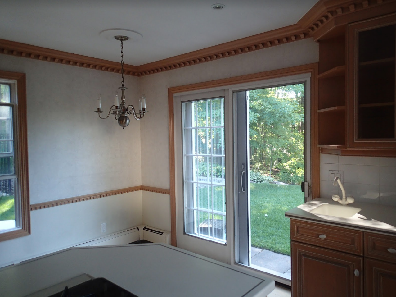 Kitchen with a light-colored countertop, cabinets, and a sliding glass door leading to a backyard.