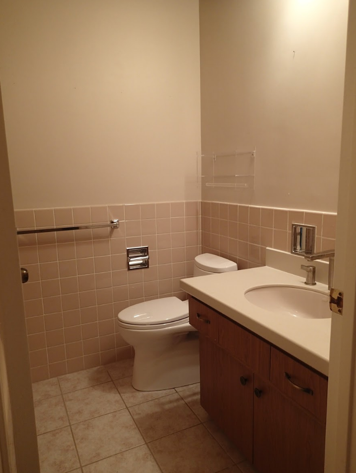 Small bathroom with pink tile walls, toilet, vanity, and beige paint.