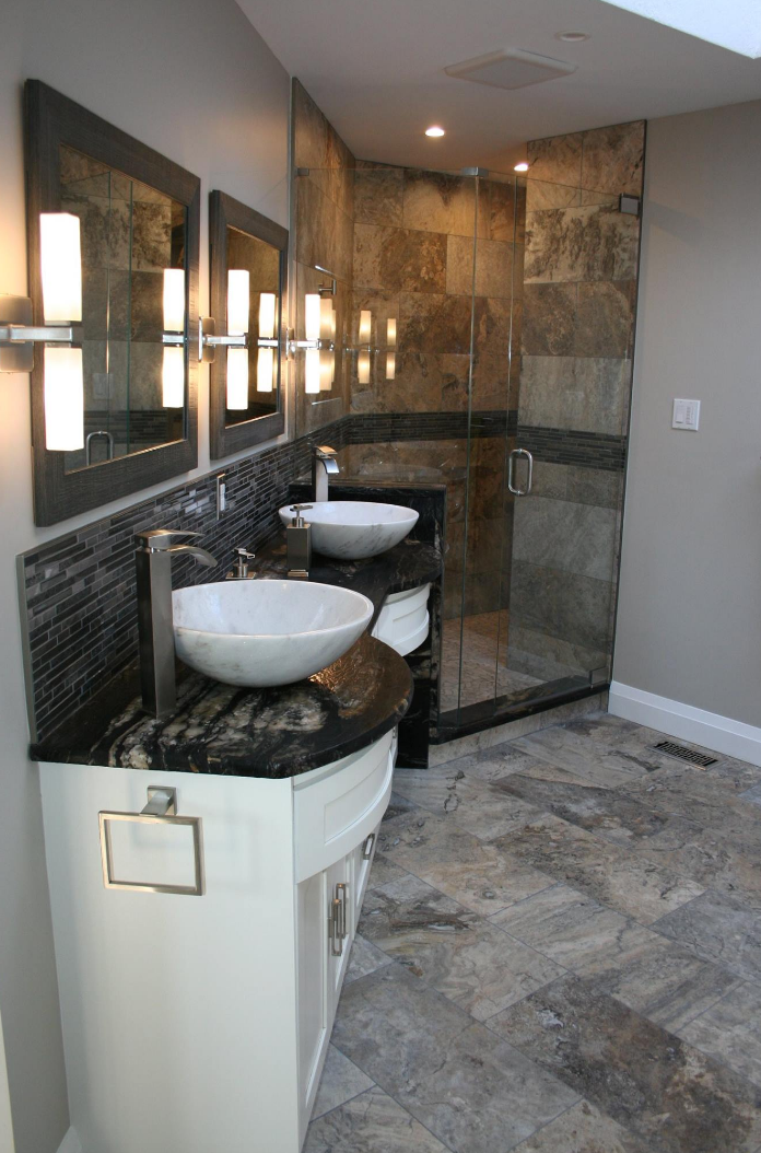 Modern bathroom with white vanities, vessel sinks, glass shower, and stone tiles.