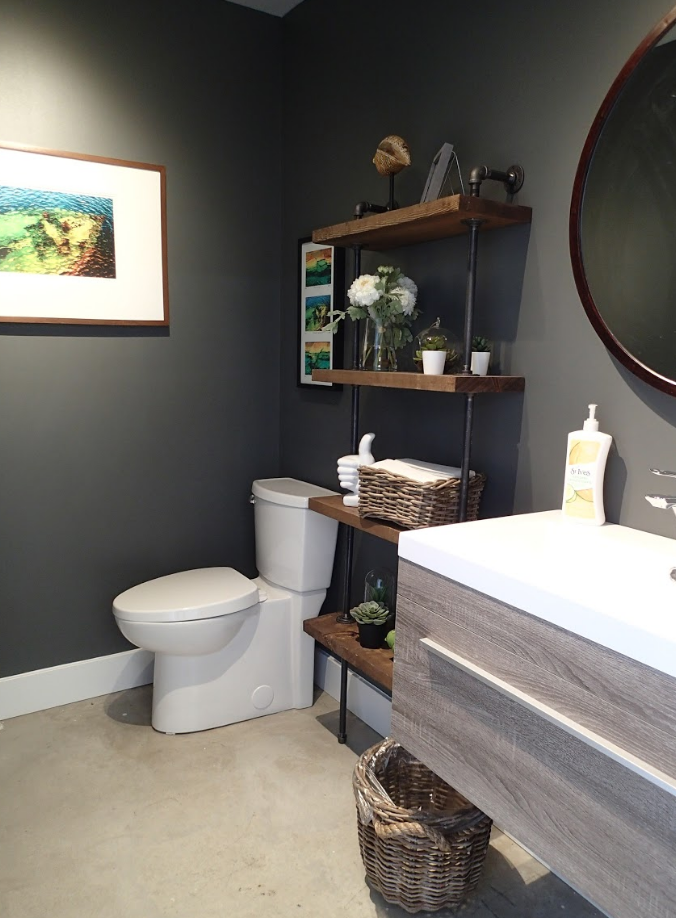 Modern bathroom with gray walls, floating shelves, toilet, and a wood-tone vanity.