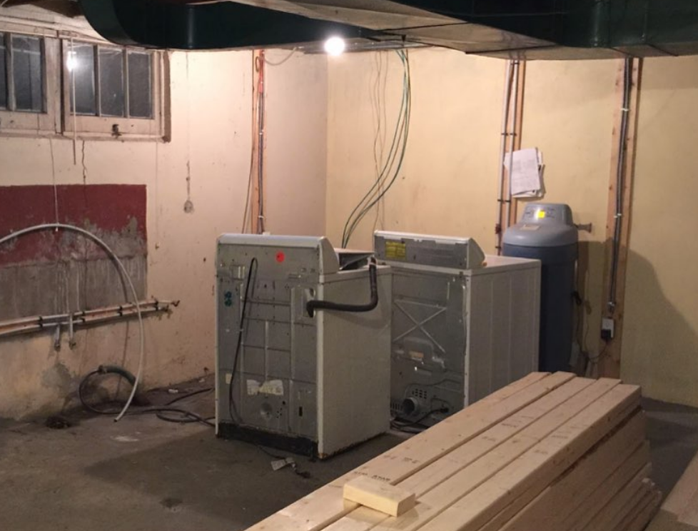 Basement laundry room with washer, dryer, water softener, and lumber.