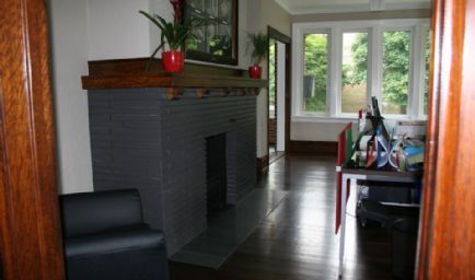 Fireplace in a room with dark wood floors, large windows, and a black chair.