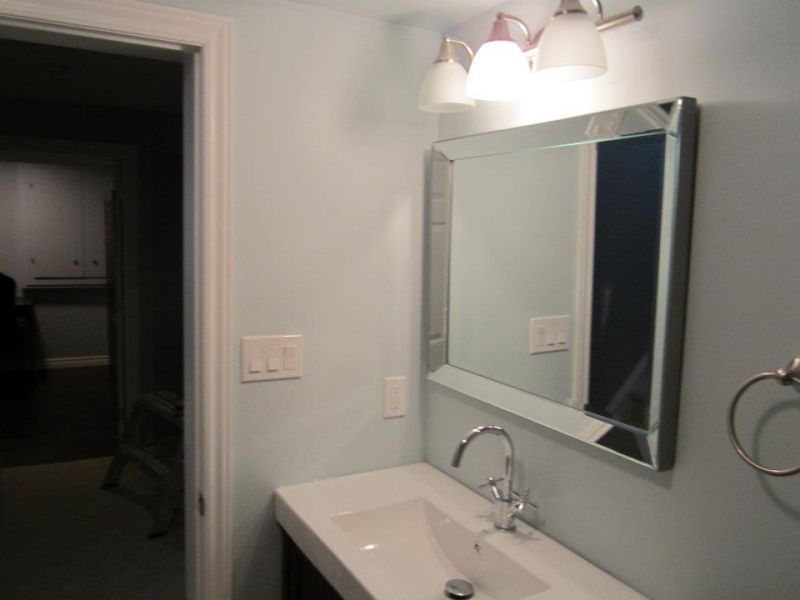 Bathroom with a rectangular mirror, white sink, silver faucet, and light blue wall.