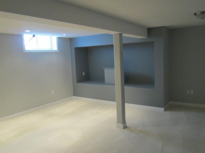 Empty basement room with gray walls, a small window, and a carpeted floor.