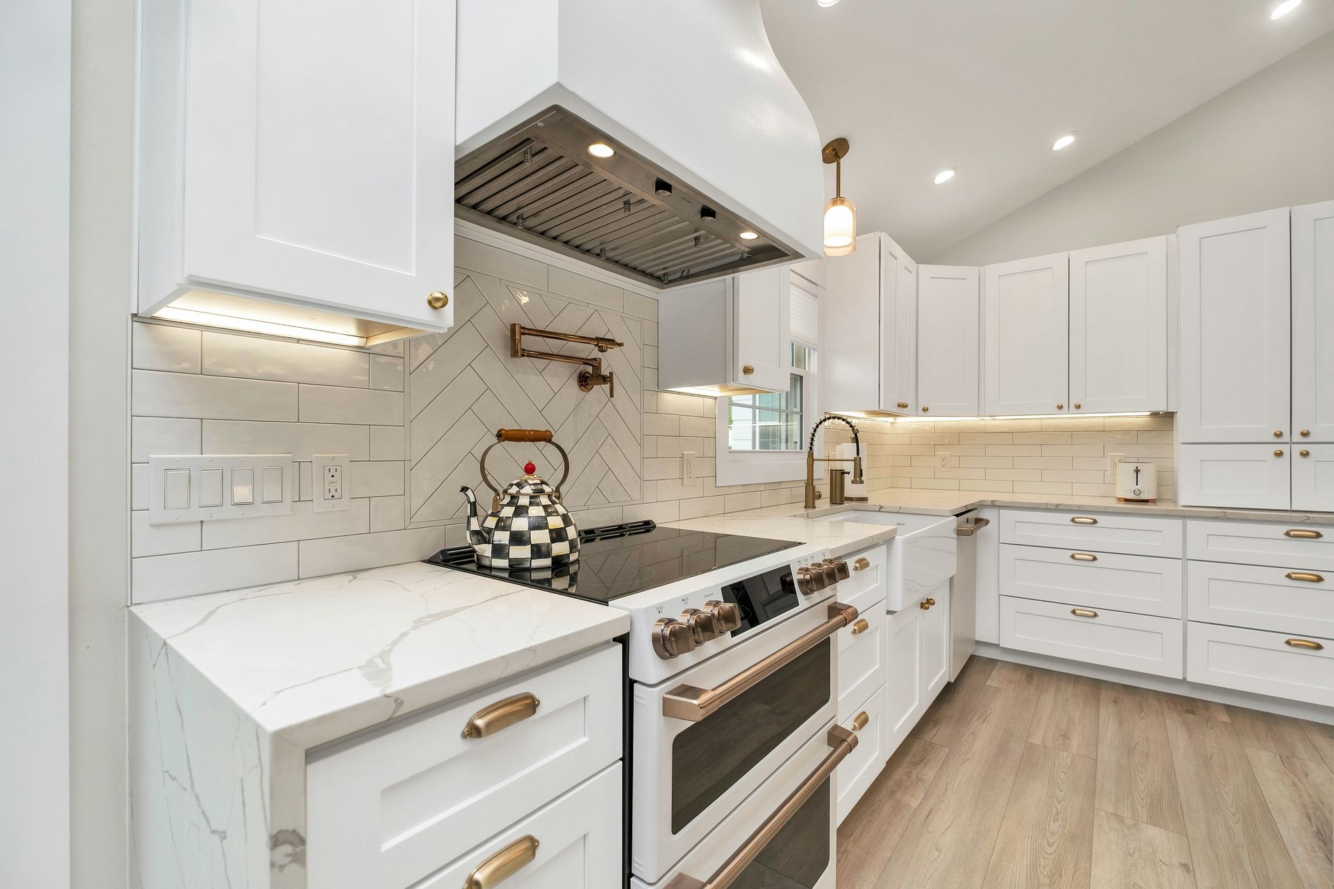 White kitchen with marble countertops, stainless steel appliances, and gold accents.