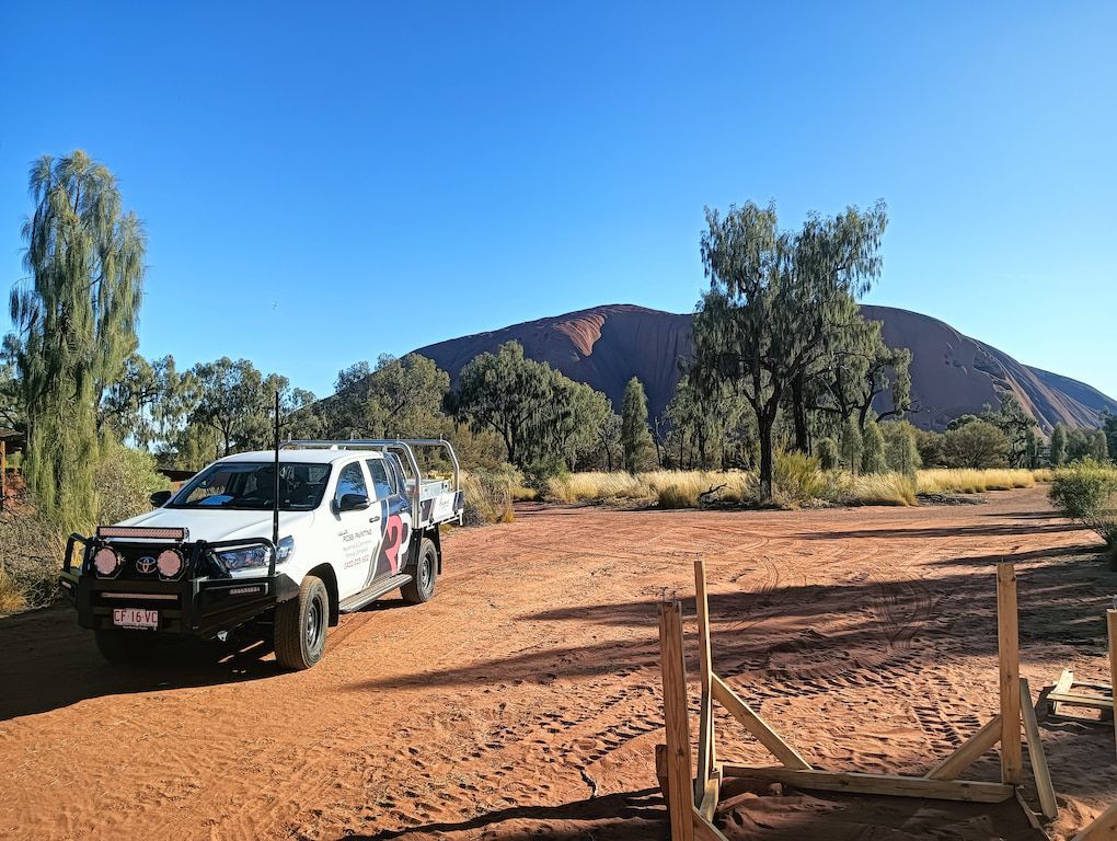 A white truck is parked on a dirt road in front of a mountain — Ross Painting In Ciccone, NT