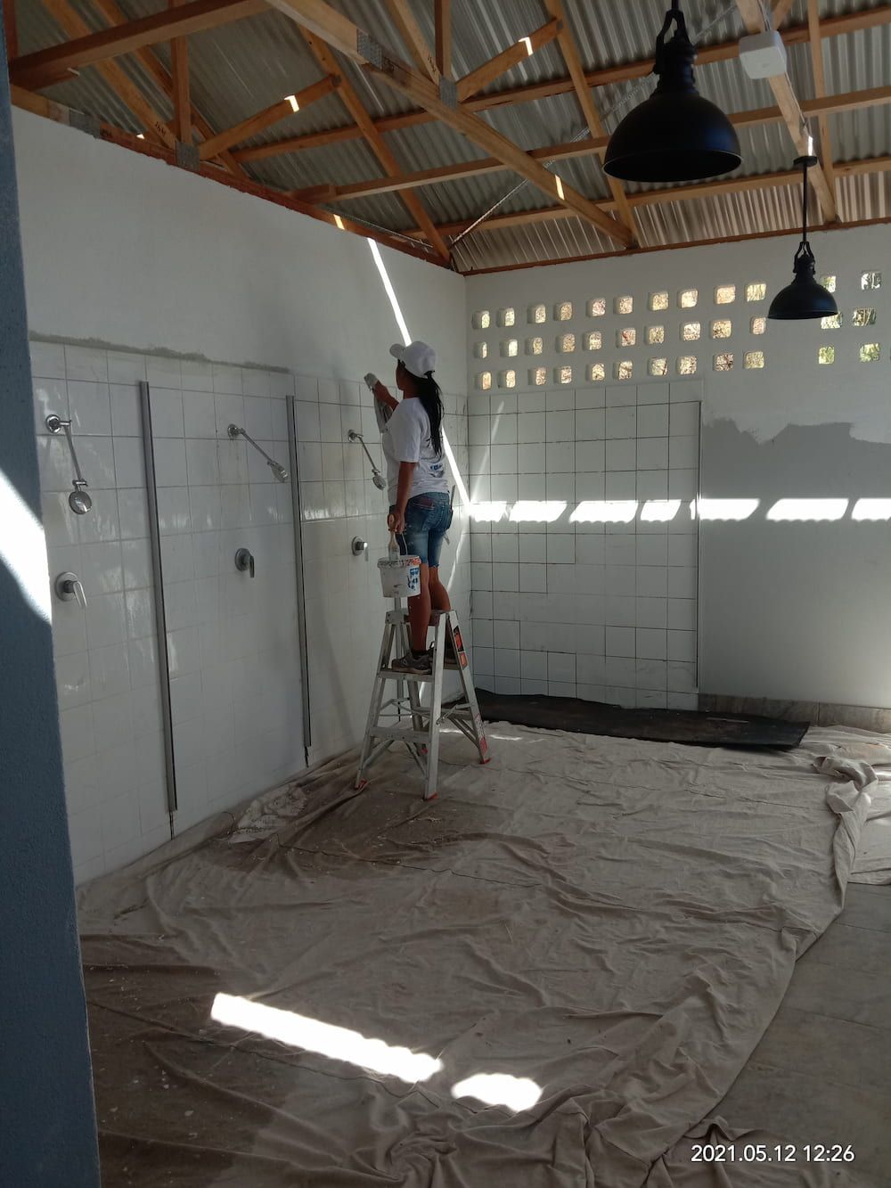 A Woman Is Standing On A Ladder Painting A Wall — Ross Painting In Ciccone, NT