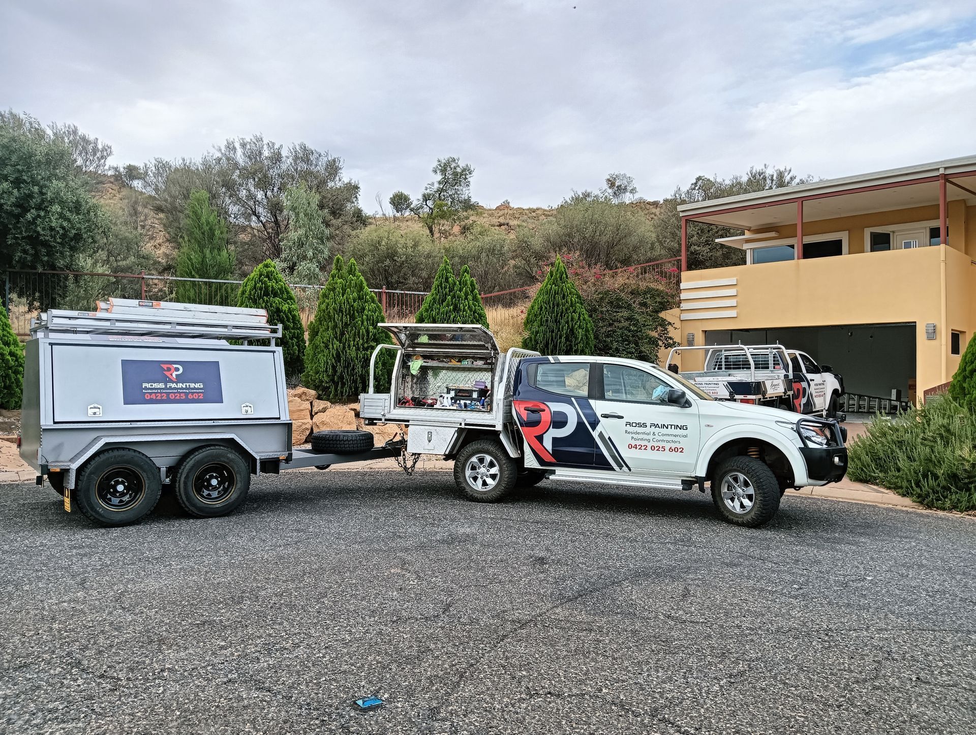 A truck with a trailer attached to it is parked in front of a house — Ross Painting In Ciccone, NT