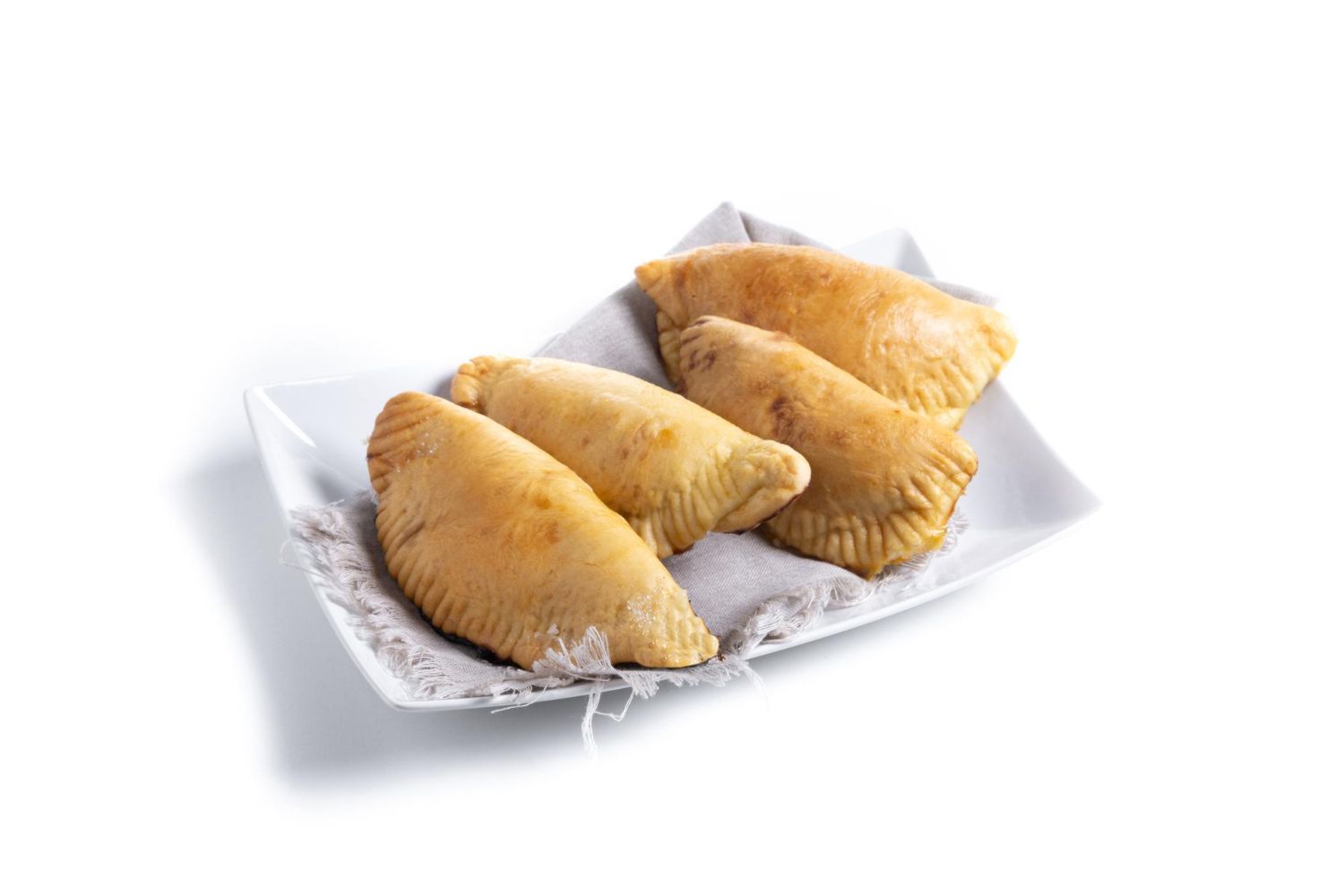 Cuatro empanadas de color marrón dorado sobre un plato blanco con un mantel estampado de color gris.