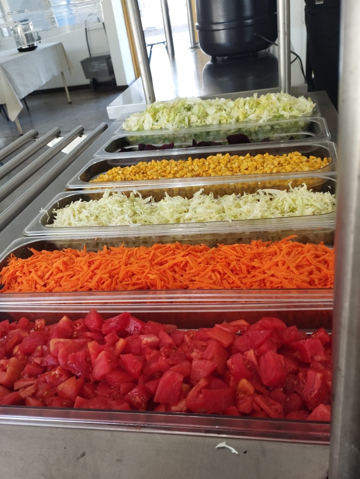Un buffet con tomates picados, zanahorias, repollo y maíz.