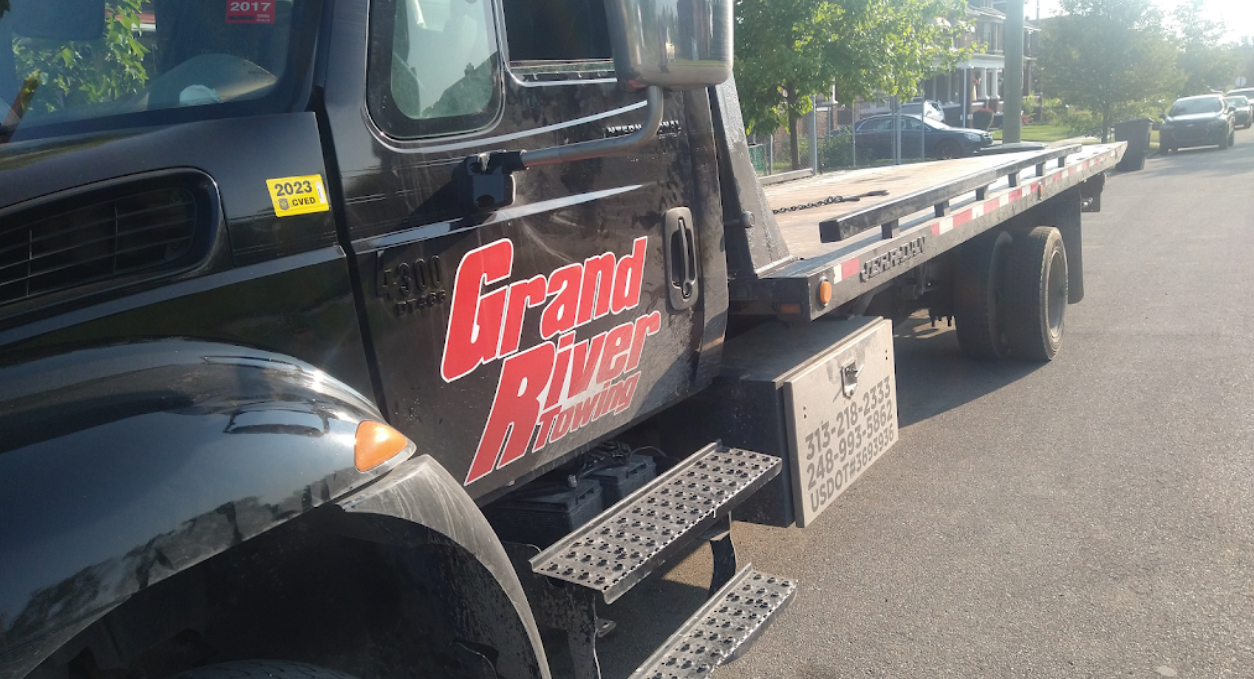 White Jeep with shredded front tire parked on a blue and yellow painted curb at night.