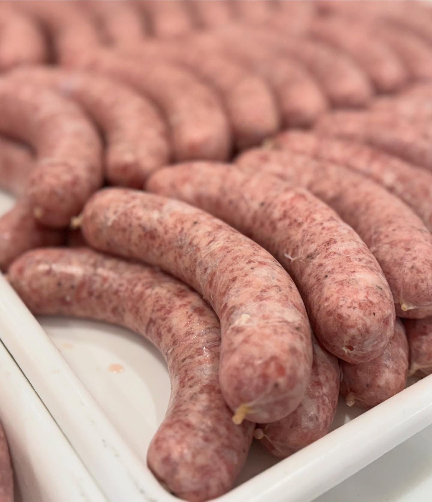 A bunch of sausages are in a white tray