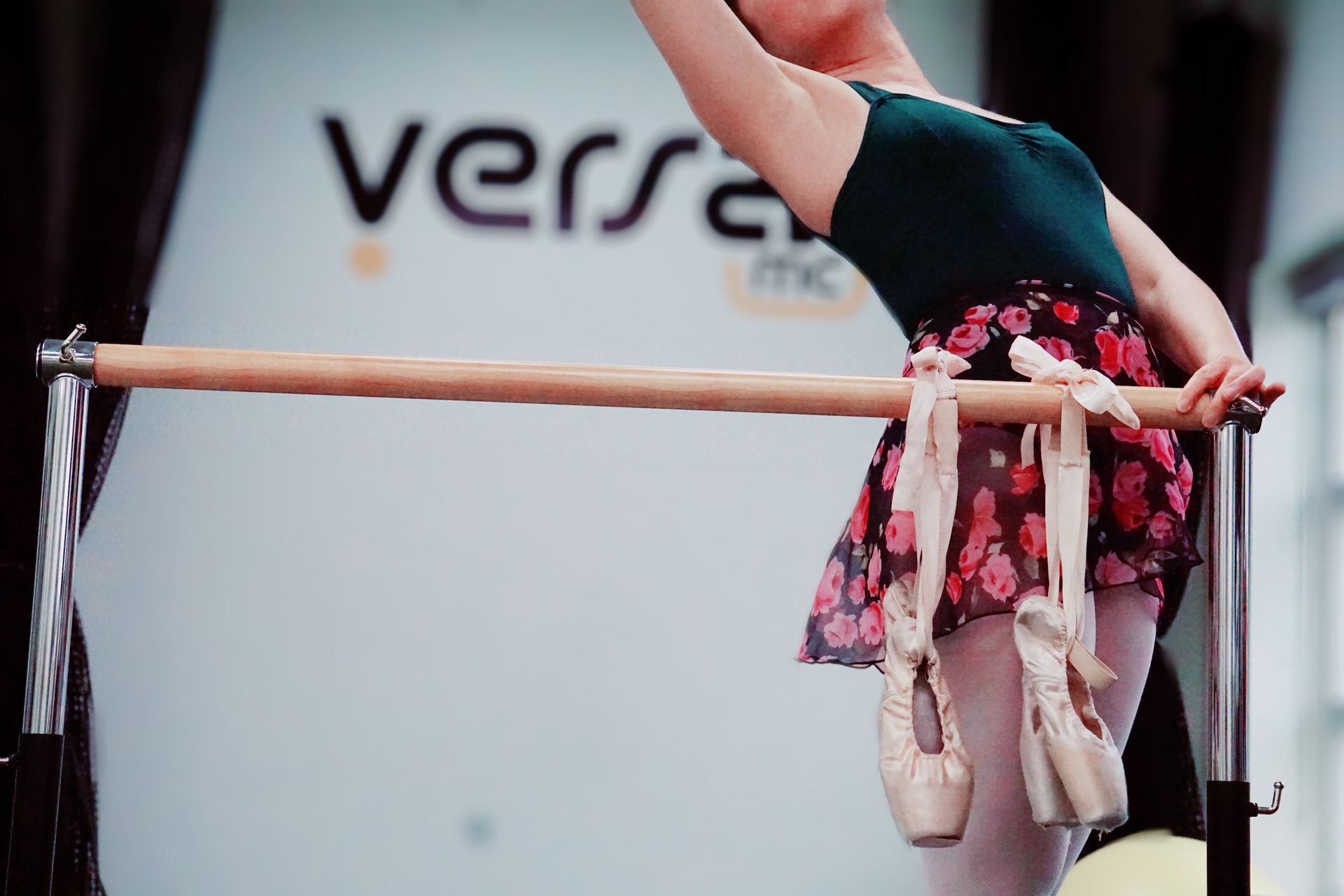 a ballerina is holding a bar with her pointe shoes hanging from it .