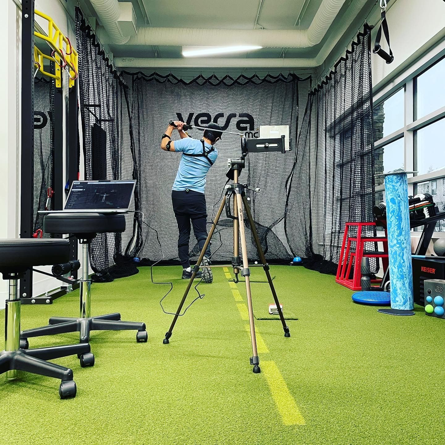 a man is standing in a gym with a camera on a tripod .