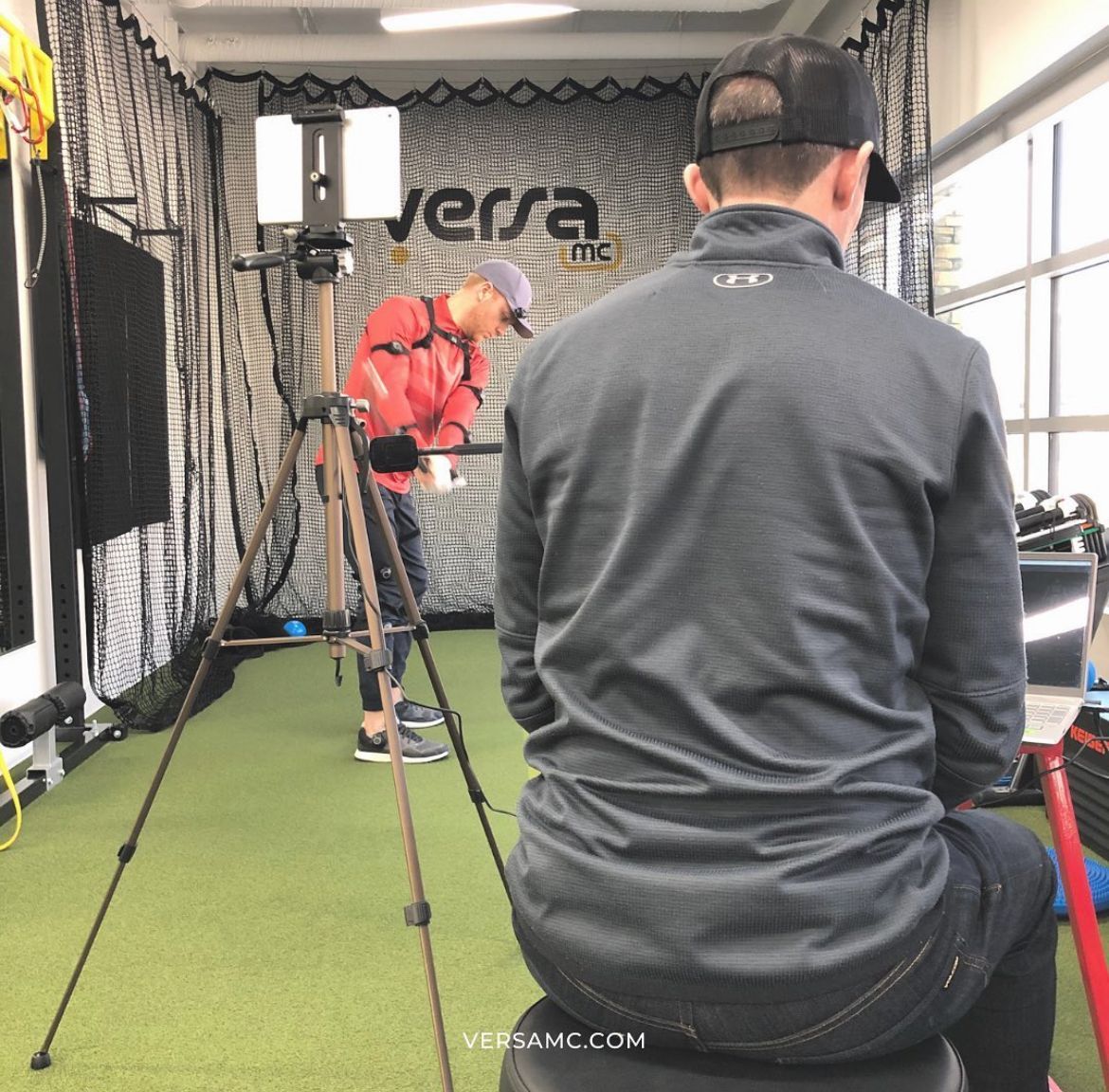 A man is sitting in front of a wall that says versa