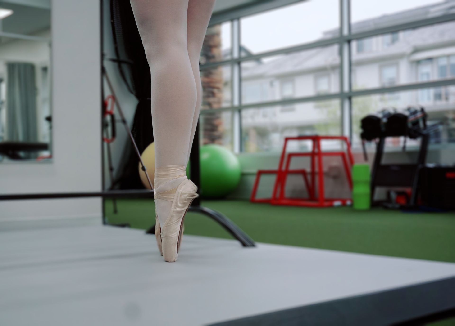 a ballerina is standing on one leg in a gym .