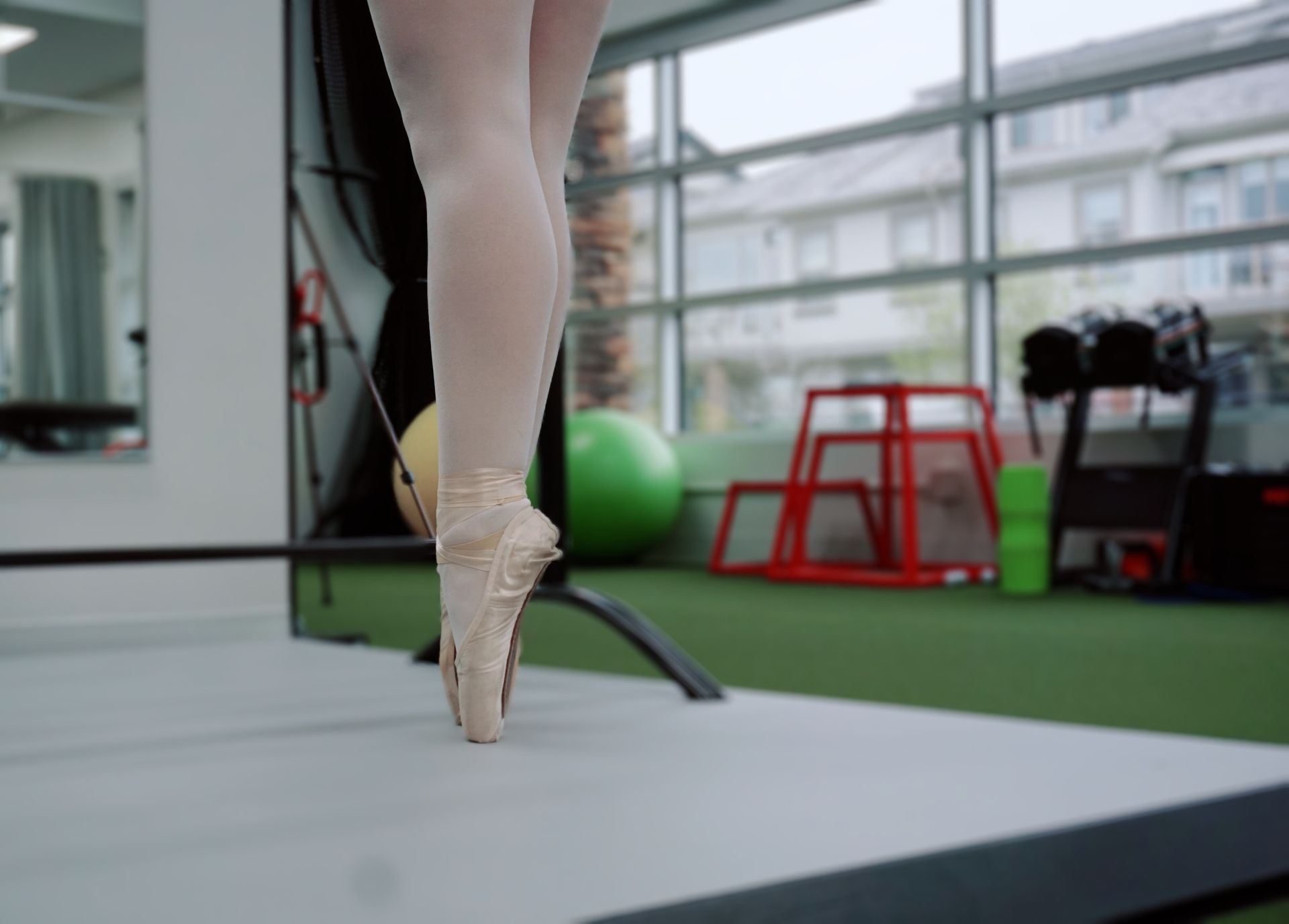 A ballerina is standing on one leg in a gym.