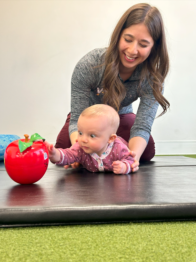 A woman is playing with a baby on a mat.