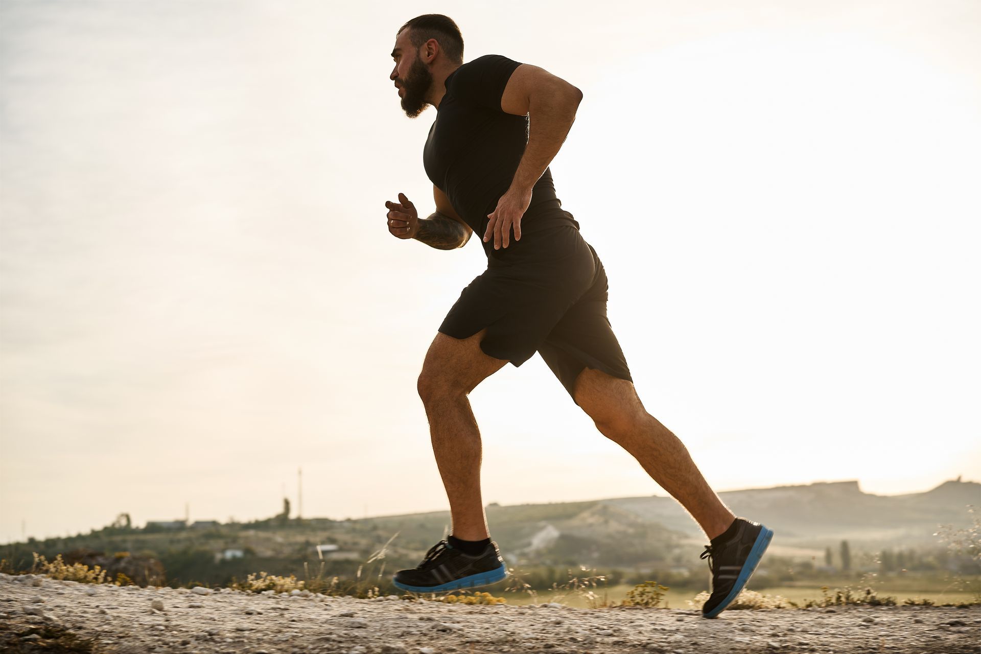 A man with a beard is running on a dirt road.