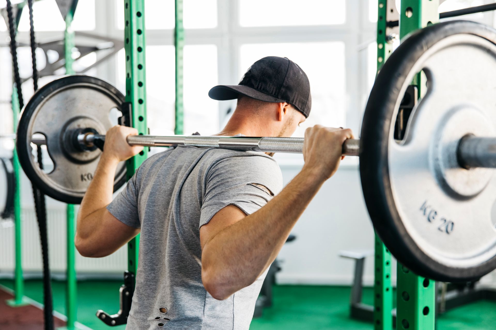 A man is squatting with a barbell on his back in a gym.