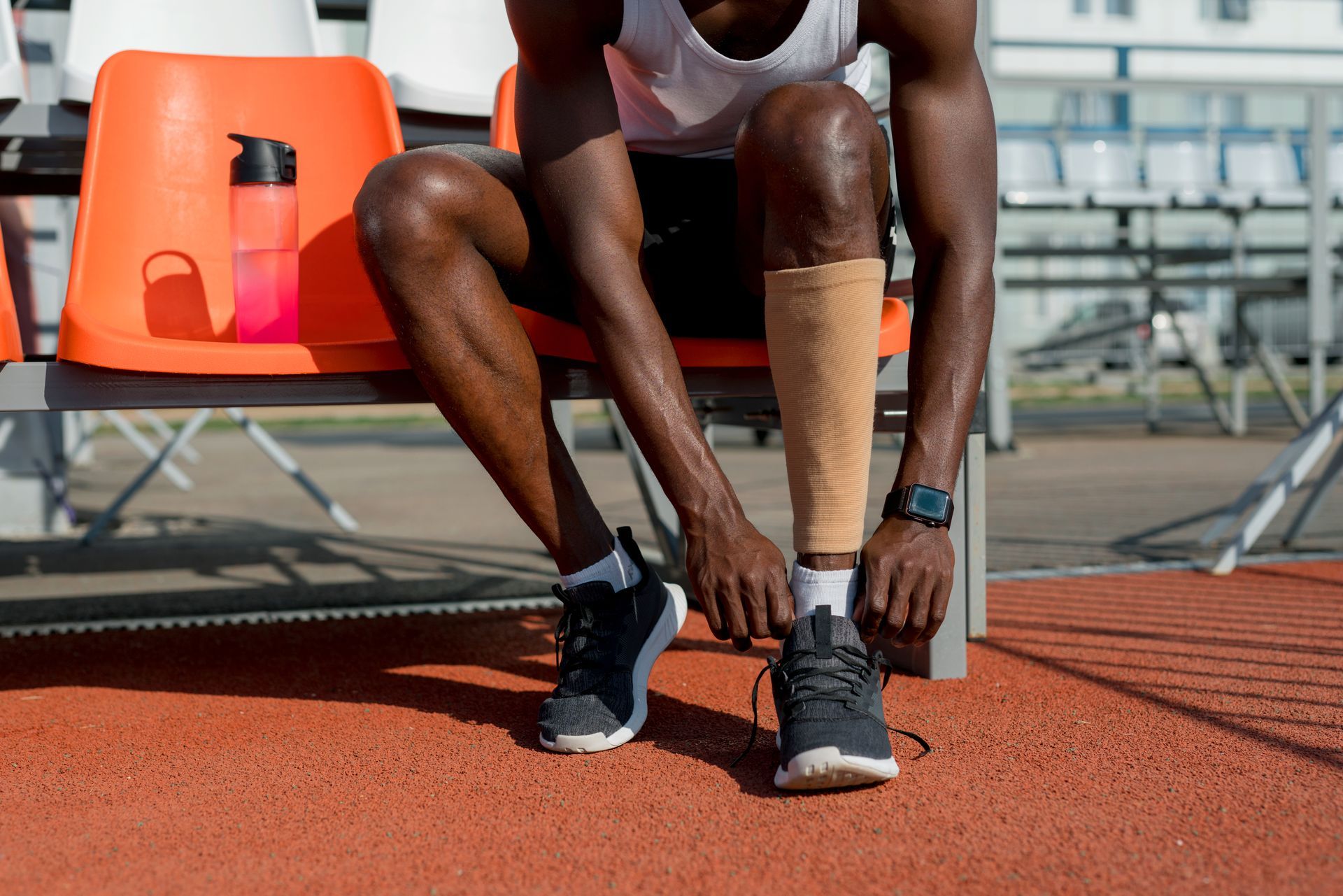 A man with a prosthetic leg is tying his shoes while sitting on a bench.