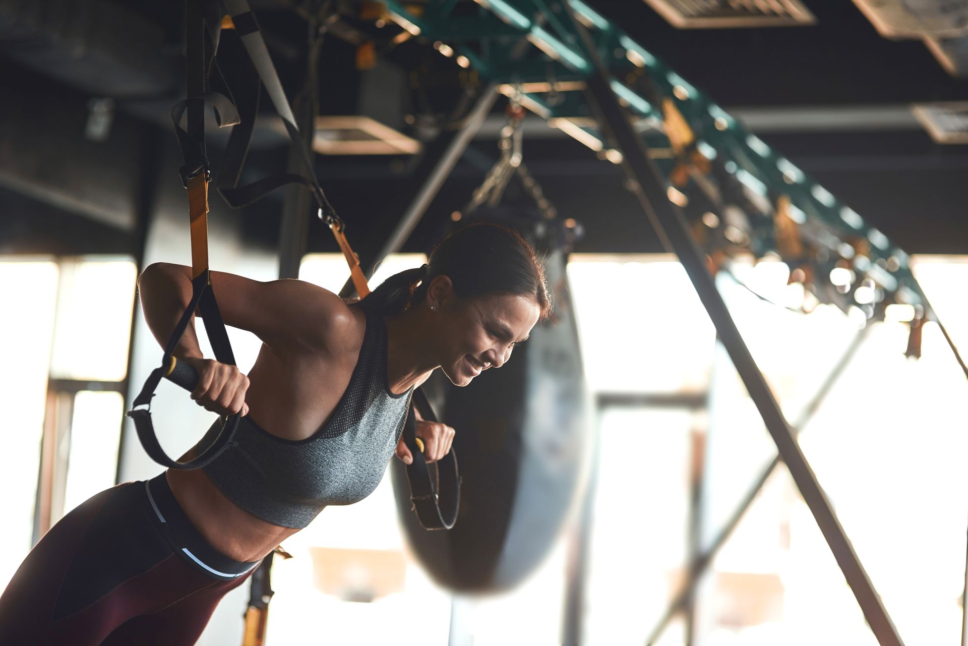 a woman is doing exercises on a suspension trainer in a gym .