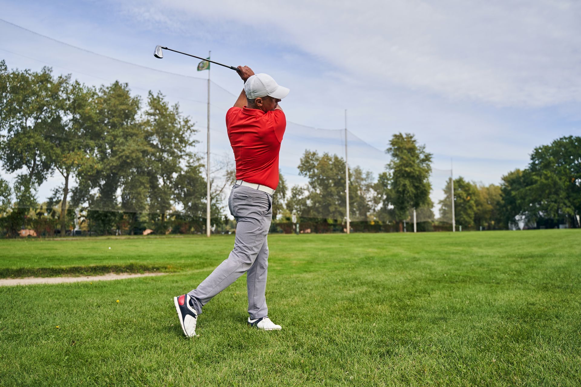 A man is swinging a golf club on a golf course.