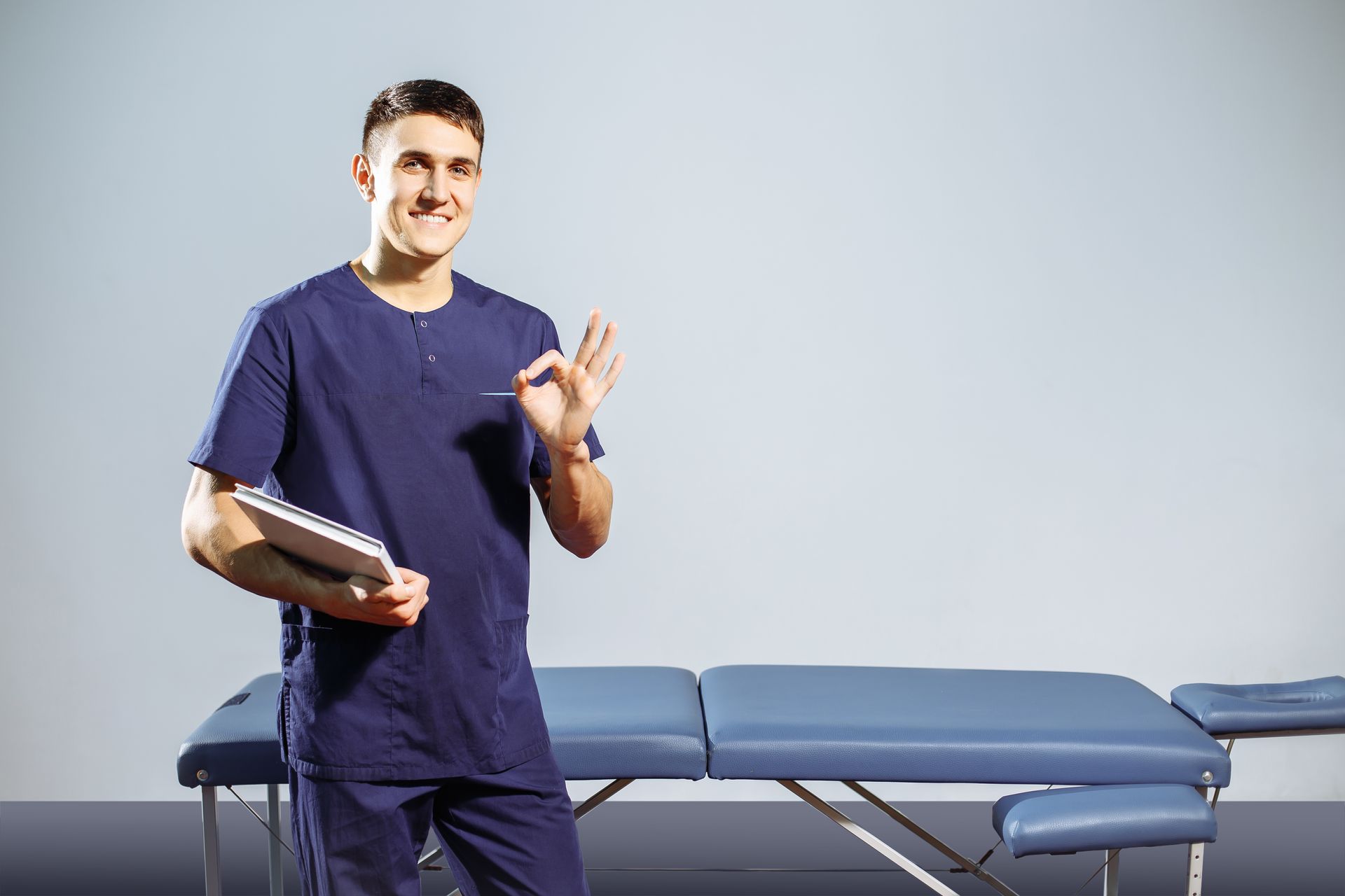 a man in a blue scrub is standing in front of a massage table .