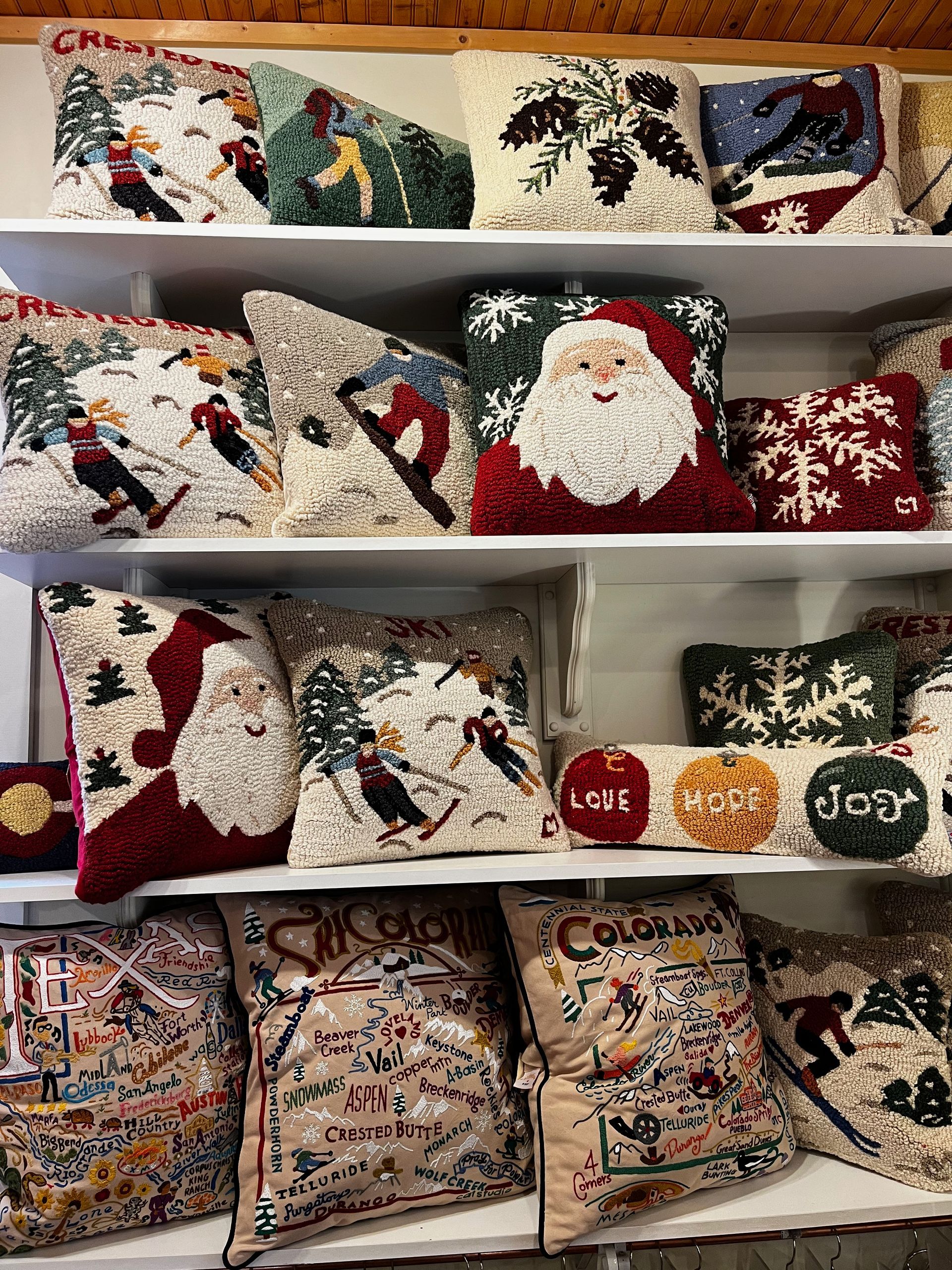 A shelf filled with lots of christmas pillows on it.