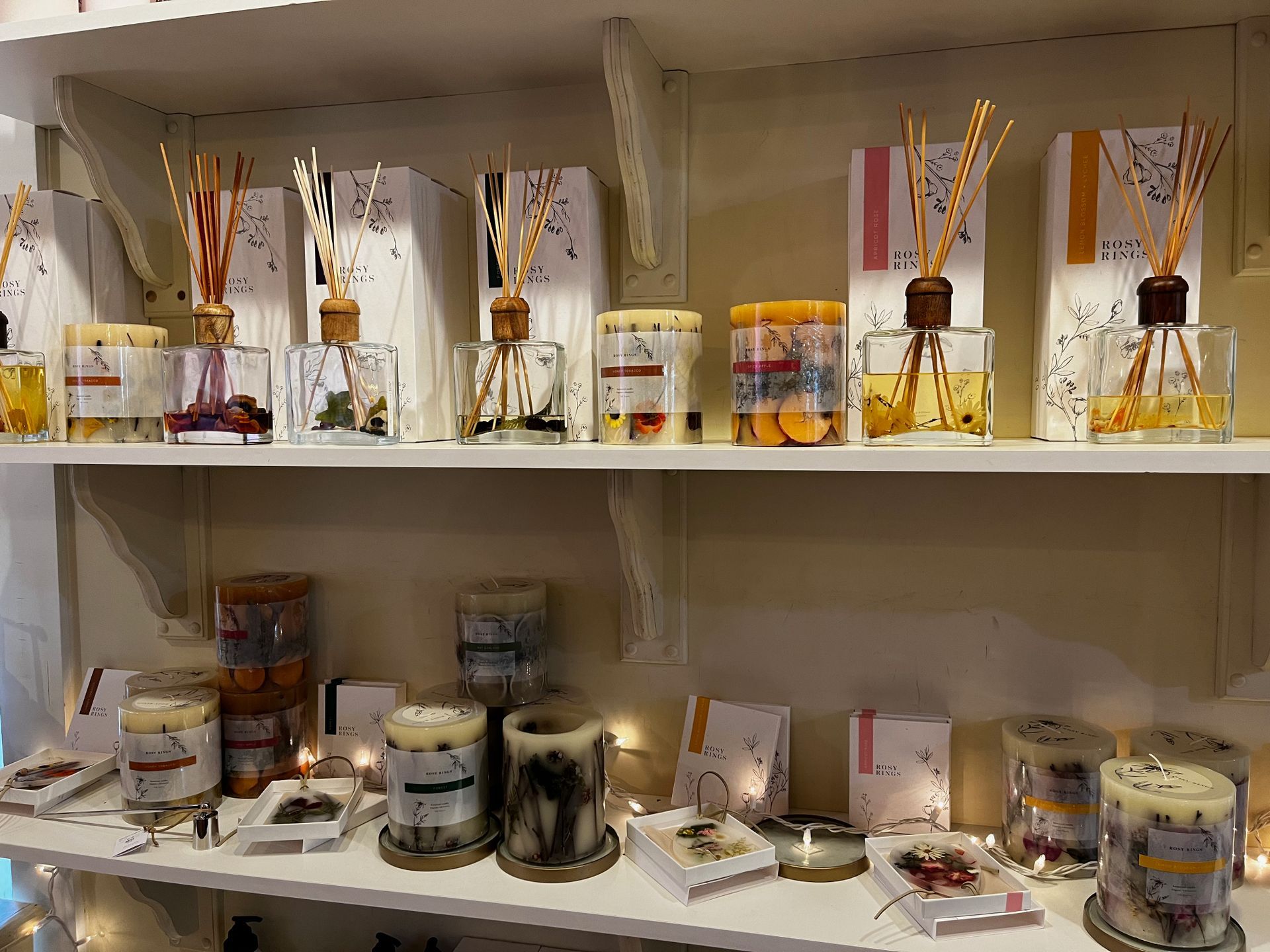 A shelf filled with candles and reed diffusers.