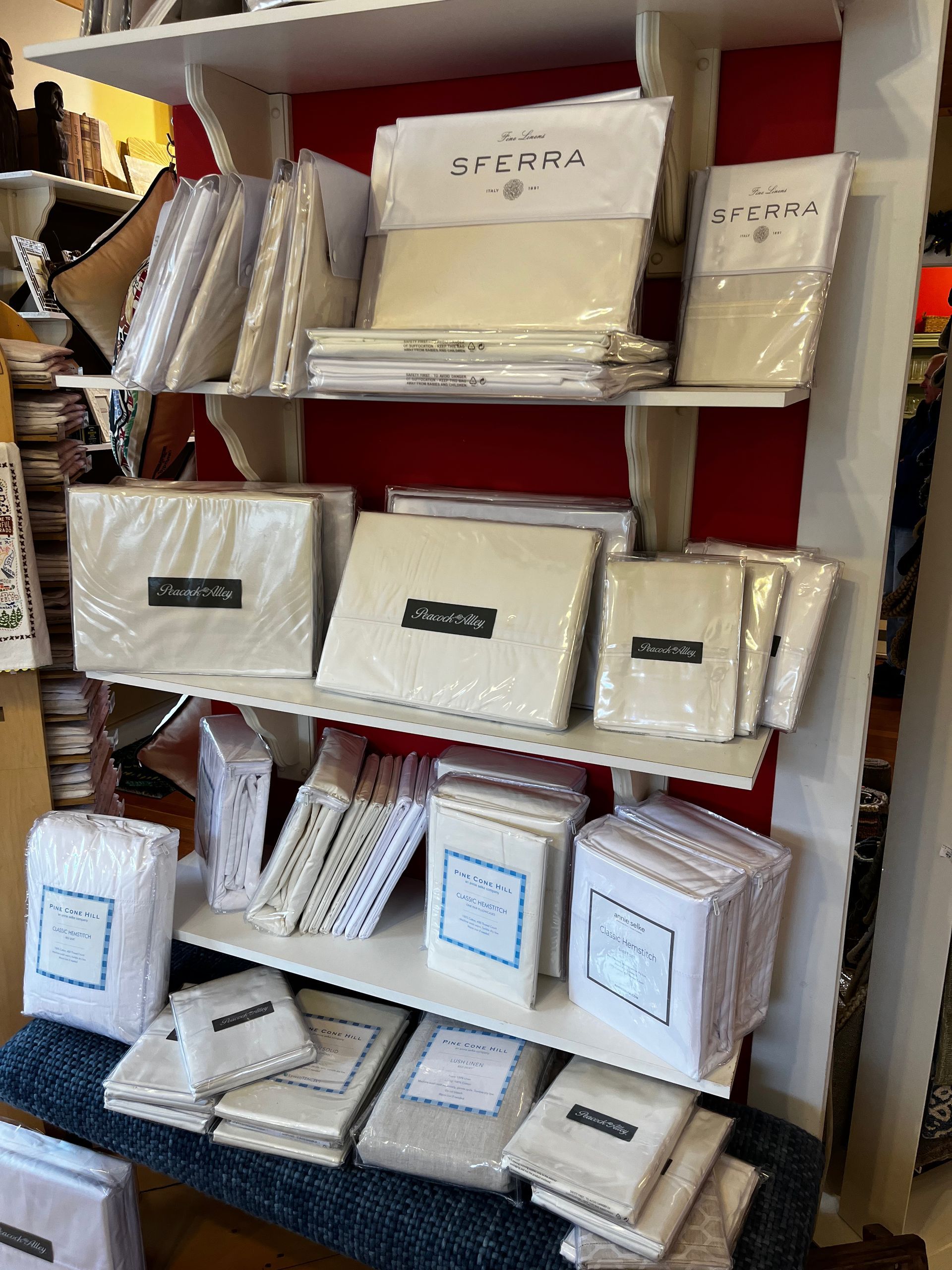 A shelf filled with lots of white sheets and pillows.