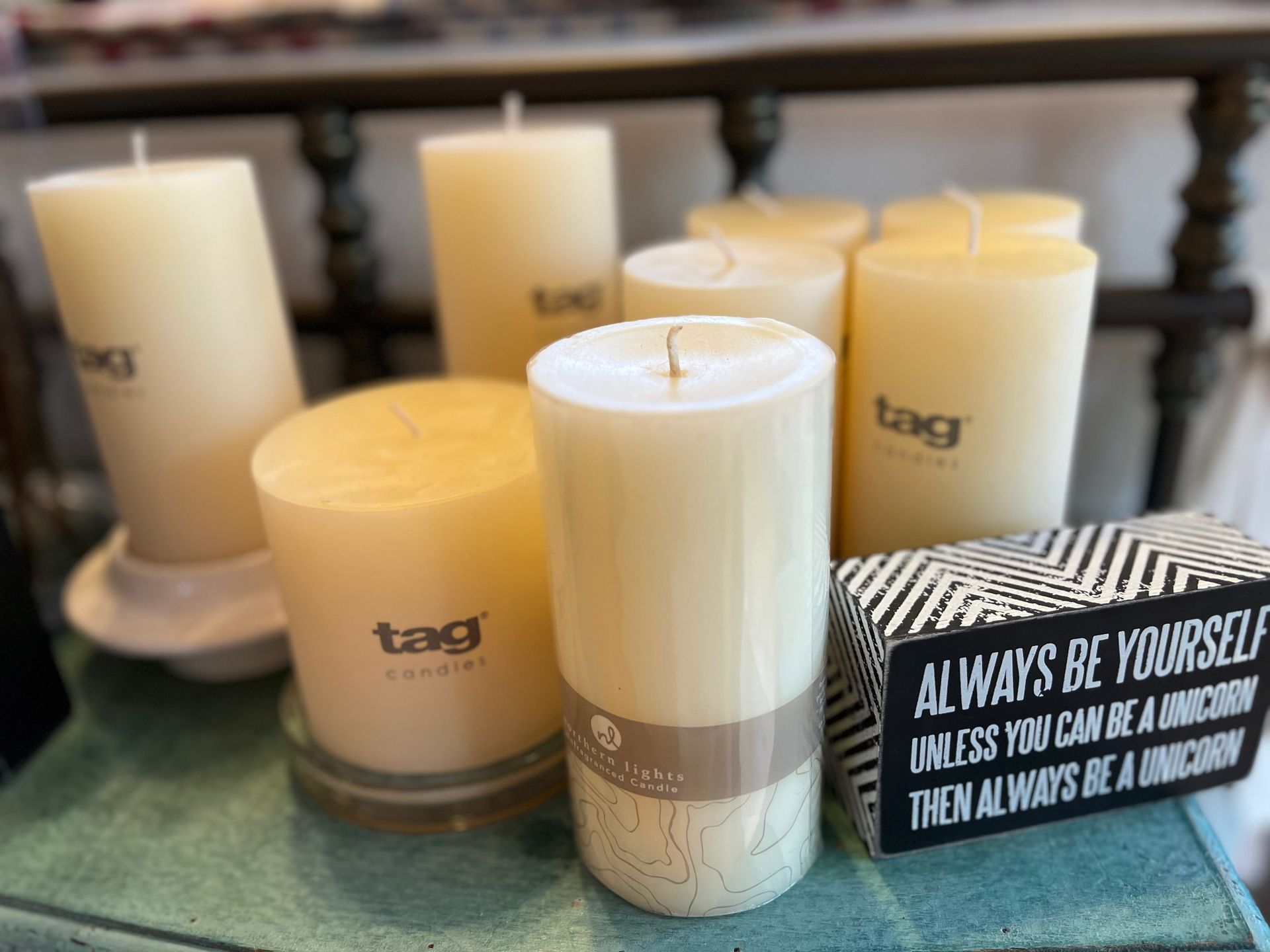 A bunch of candles are sitting on a table next to a sign that says always be yourself.