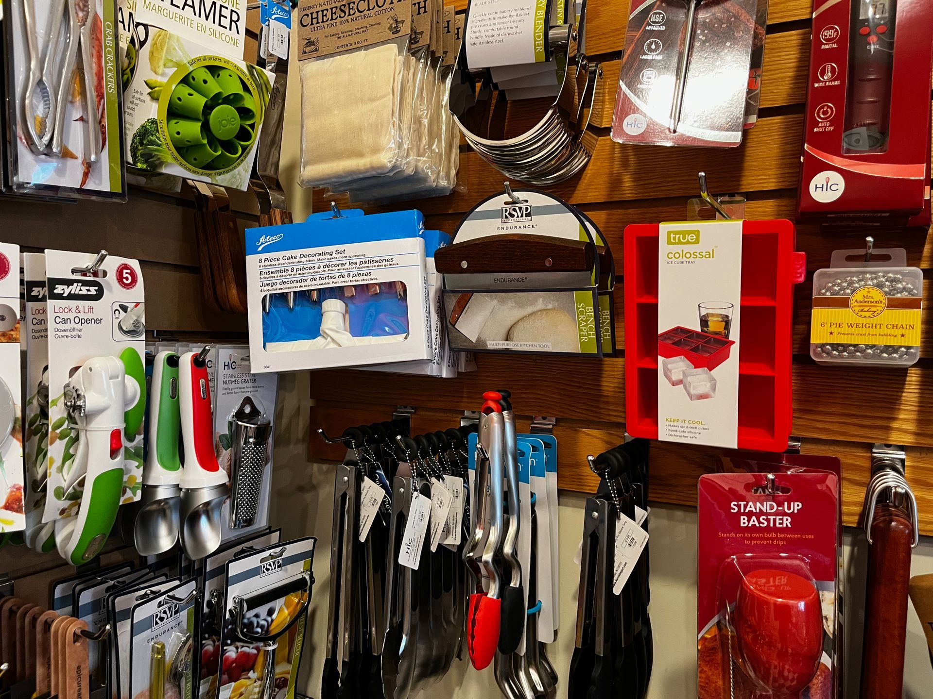 A variety of kitchen utensils are hanging on a wall in a store.