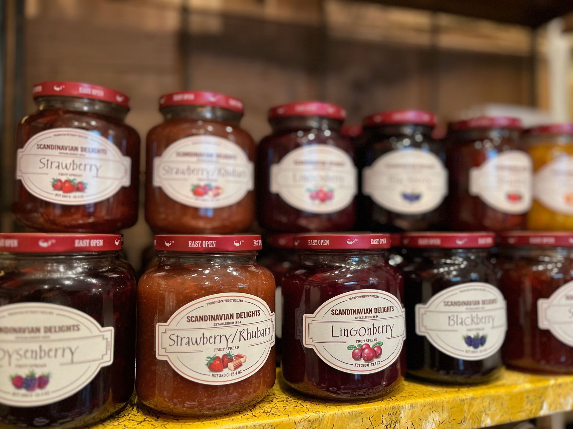 A shelf filled with jars of jam of different flavors.
