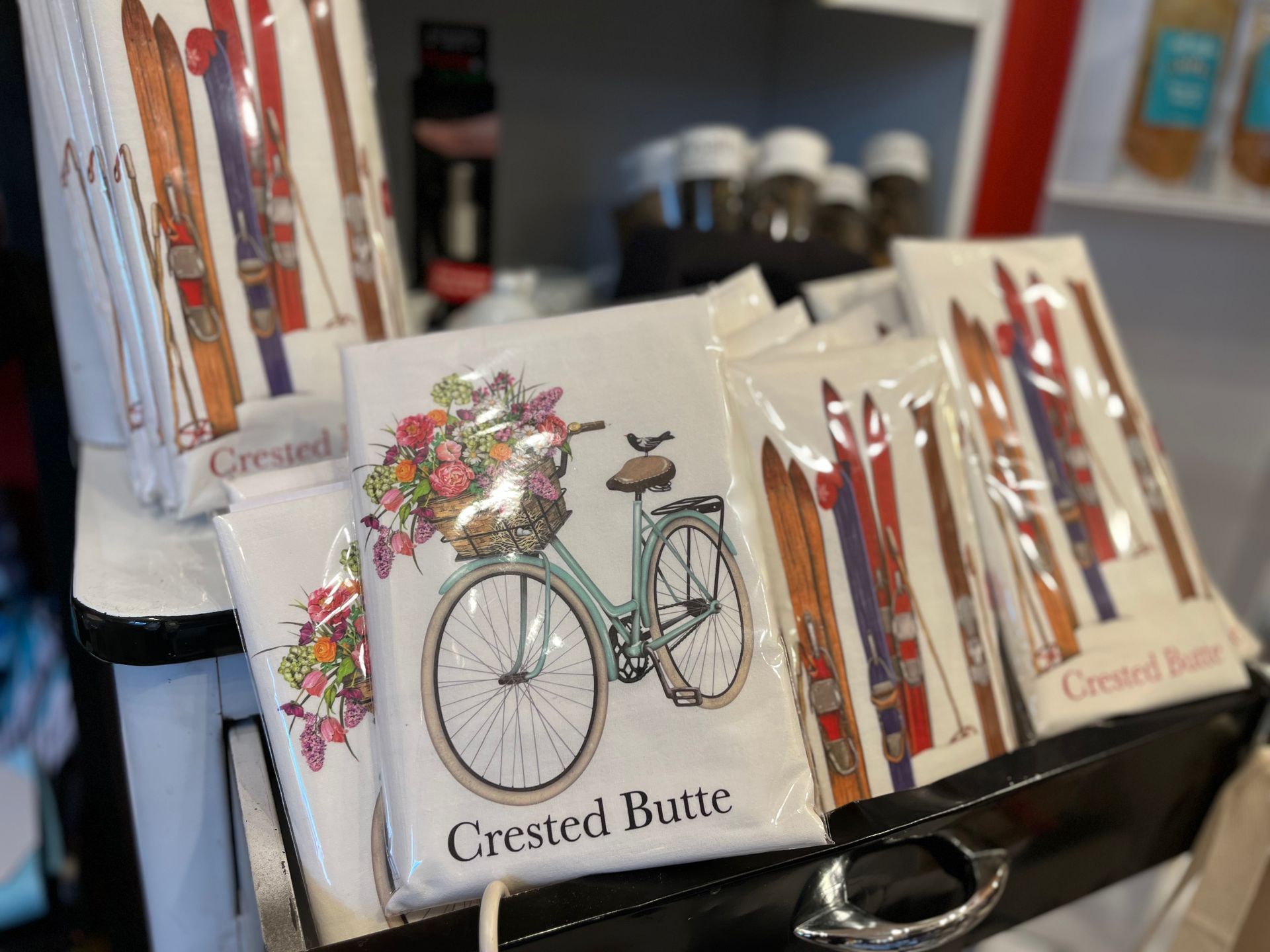 A bicycle with a basket of flowers is on a t-shirt in a store.