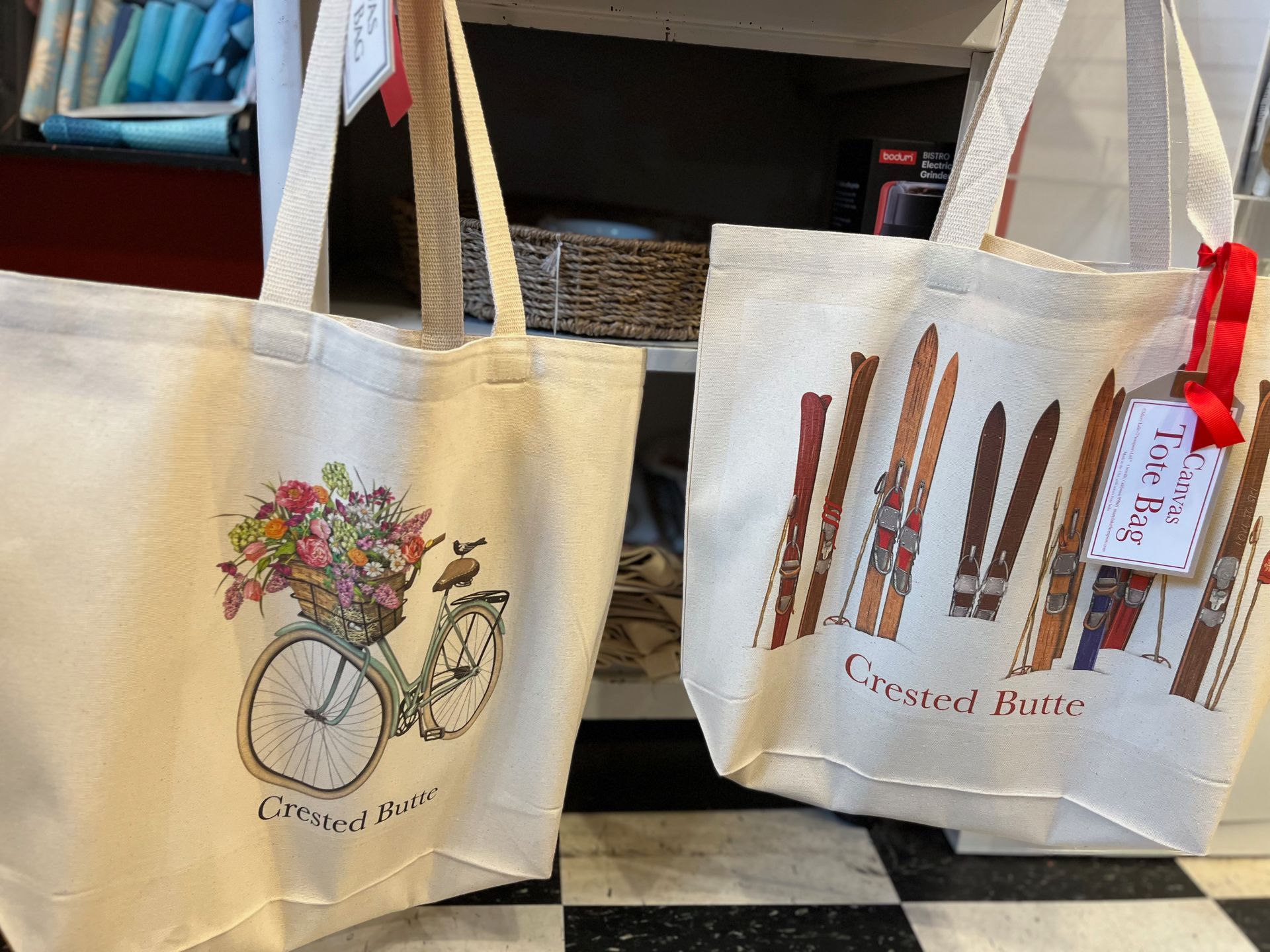 Two tote bags are sitting next to each other on a checkered floor.