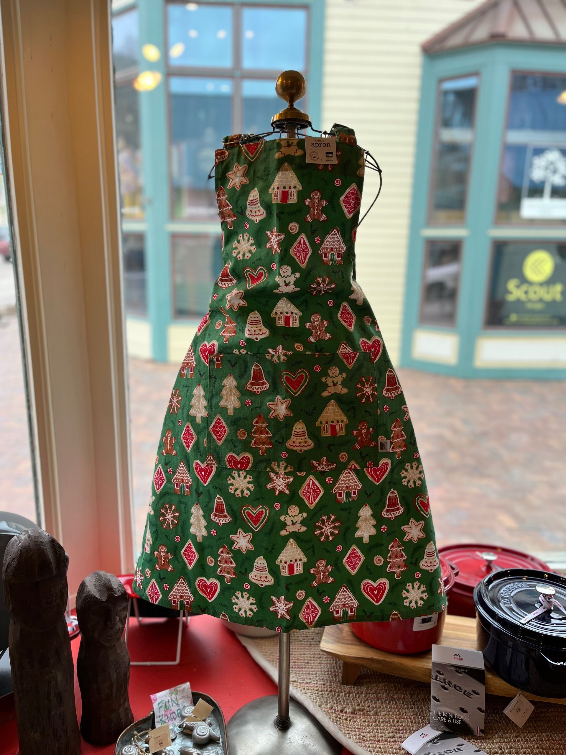 A green christmas dress is on a mannequin in front of a window