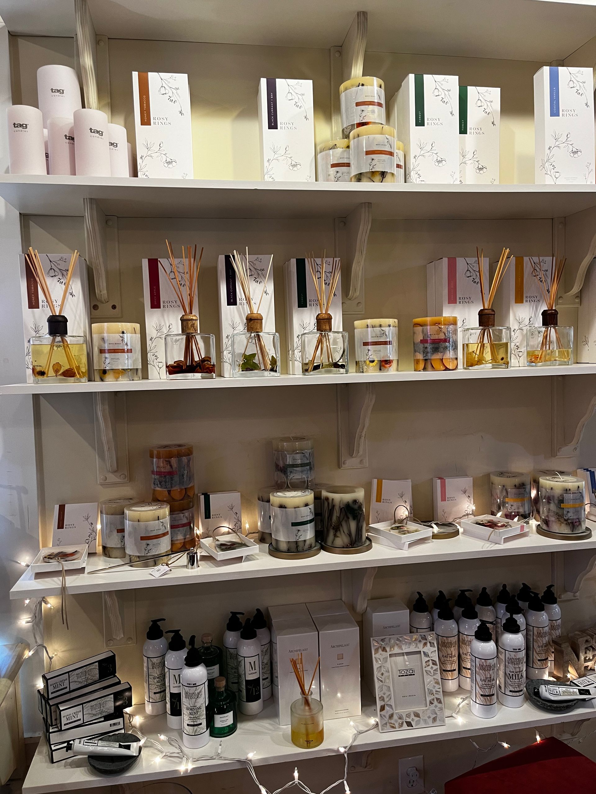 A shelf filled with lots of different types of candles.