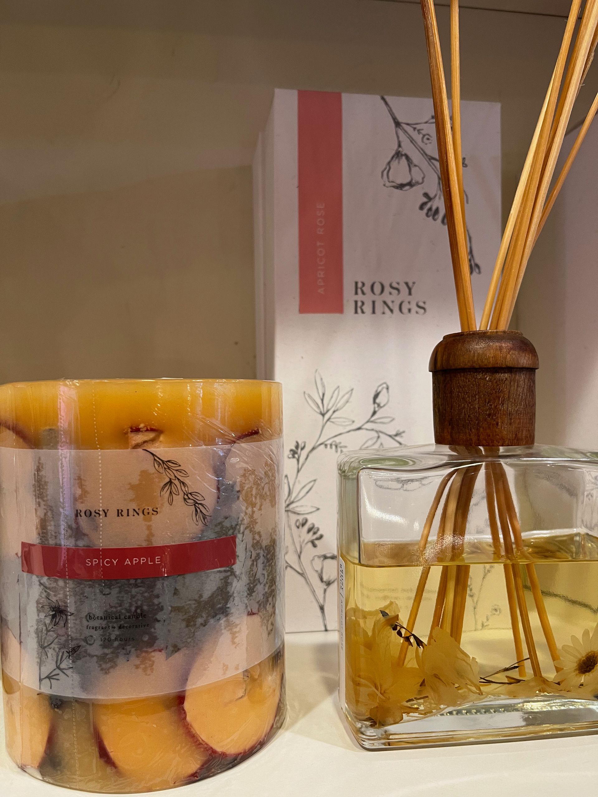 A bottle of reed diffuser next to a candle on a table.