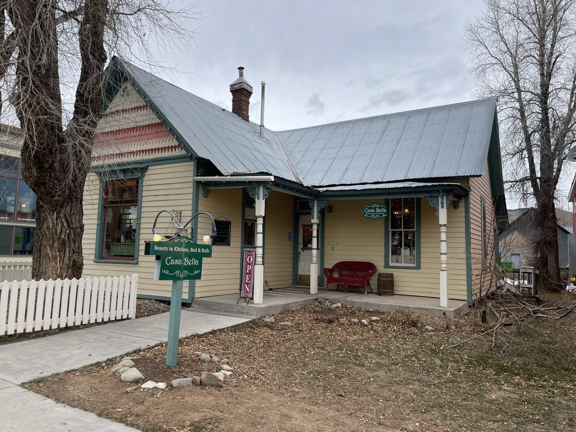A small yellow house with a metal roof and a porch.